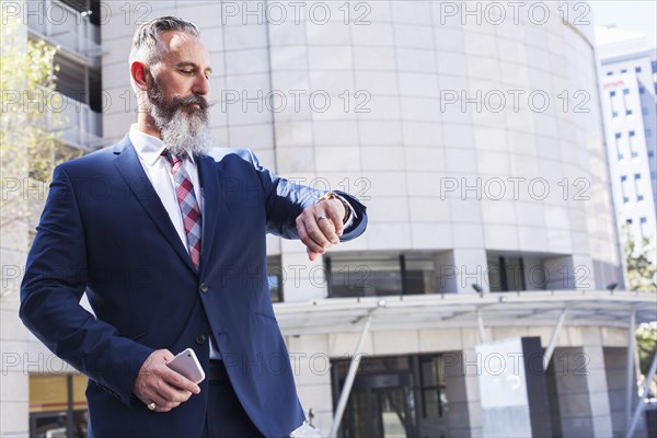 Caucasian businessman checking wristwatch outdoors