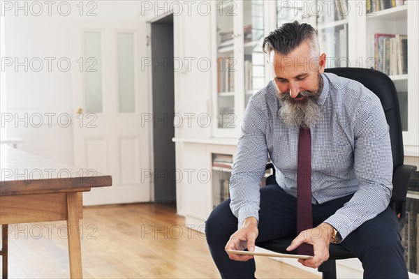 Caucasian businessman sitting on chair using digital tablet