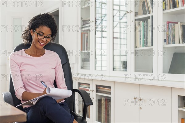 Mixed Race woman writing on notepad