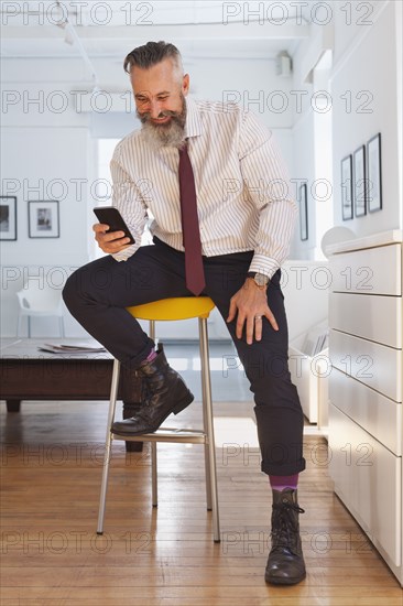 Smiling Caucasian businessman texting on cell phone