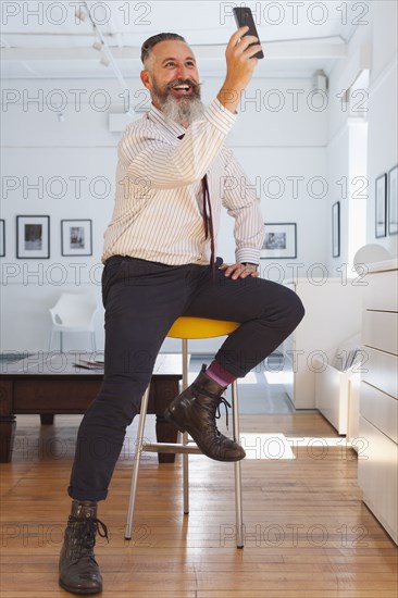 Smiling Caucasian businessman posing for cell phone selfie