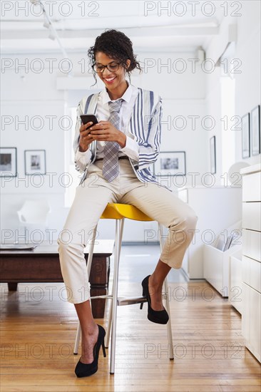 Smiling Mixed Race woman texting on cell phone