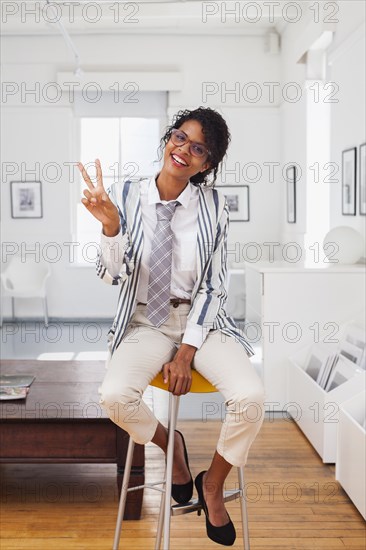 Mixed Race businesswoman gesturing peace