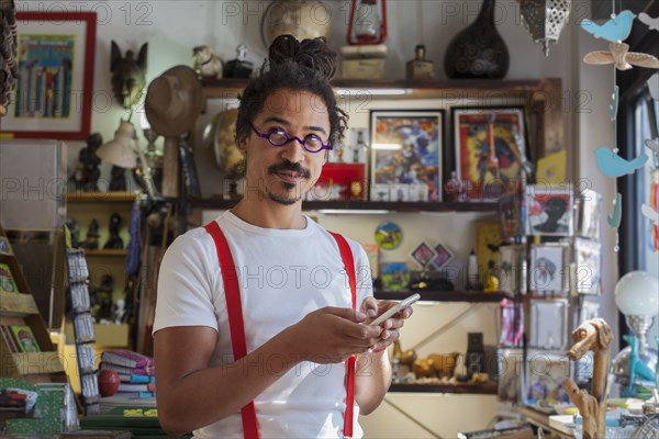 Curious mixed race man wearing suspenders texting on cell phone