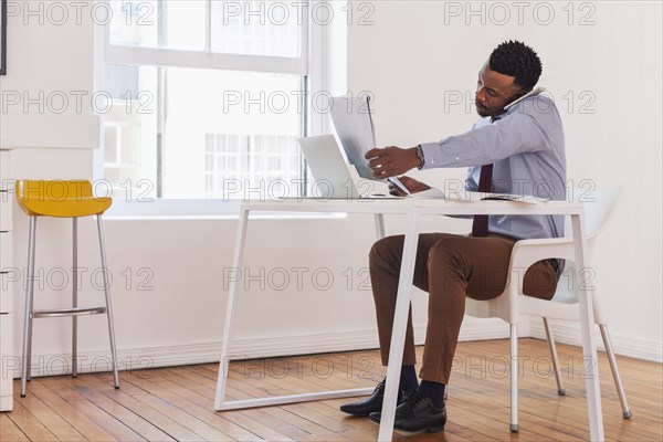 Black businessman talking on cell phone and reading notepad