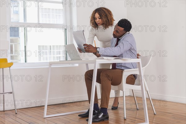 Business people talking on cell phone and reading notepad