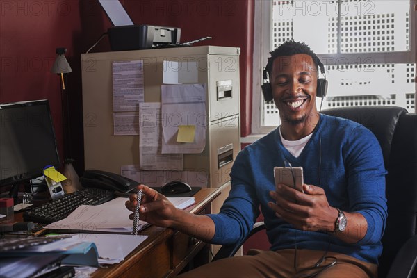 Black man listening to cell phone with headphones