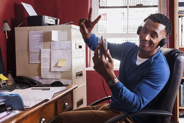 Black man listening to cell phone with headphones