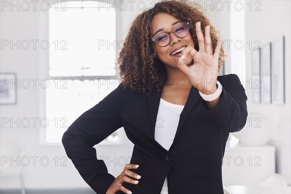 Mixed race woman gesturing okay in gallery