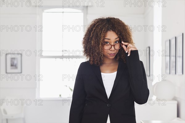 Mixed race woman peering over eyeglasses in gallery