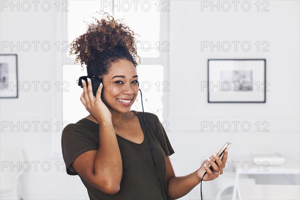 Mixed race woman listening to cell phone with headphones