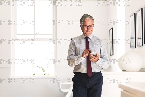 Smiling Caucasian businessman texting on cell phone
