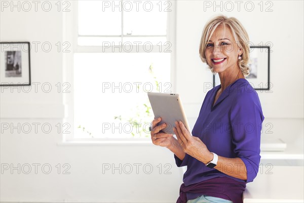Portrait of smiling Caucasian woman holding digital tablet