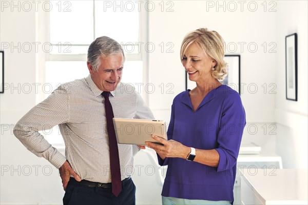 Smiling Caucasian man and woman using digital tablet