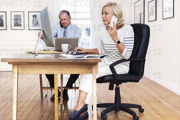 Caucasian businessman and businesswoman talking on cell phones