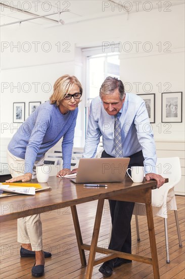 Caucasian business people leaning on table using laptop