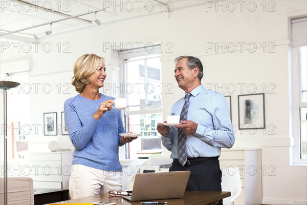 Caucasian businessman and businesswoman drinking coffee