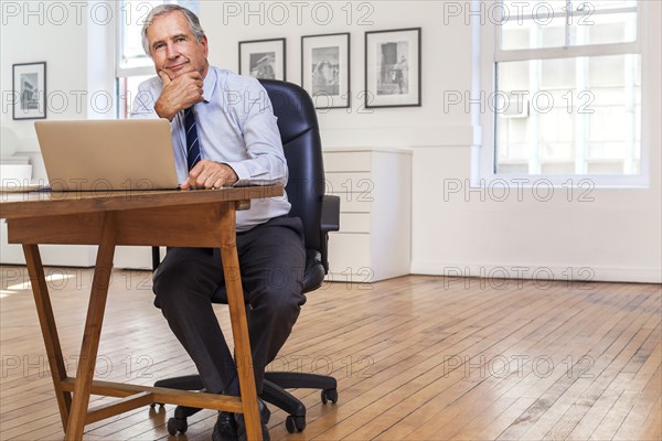 Portrait of smiling Caucasian businessman using laptop