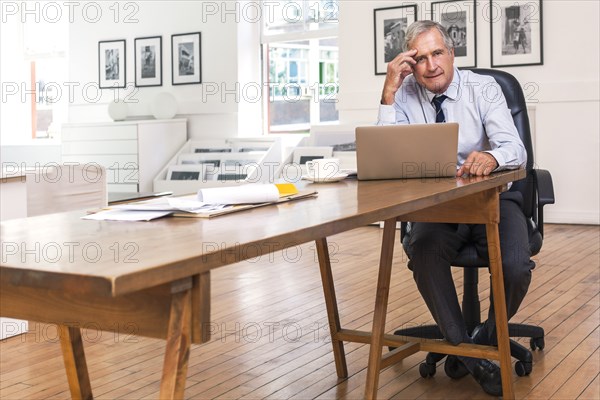 Portrait of frustrated Caucasian businessman using laptop