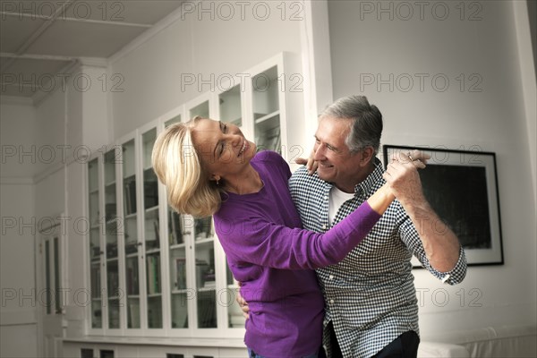 Smiling Caucasian couple dancing in home