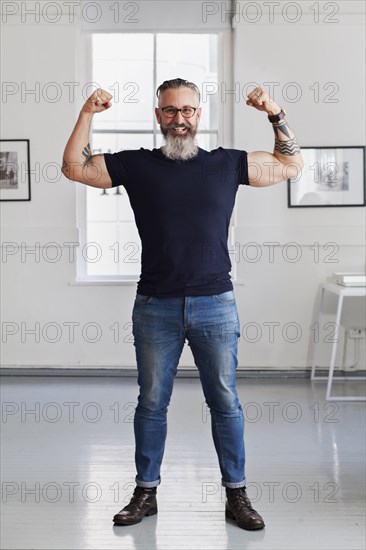 Smiling muscular Caucasian hipster man flexing biceps