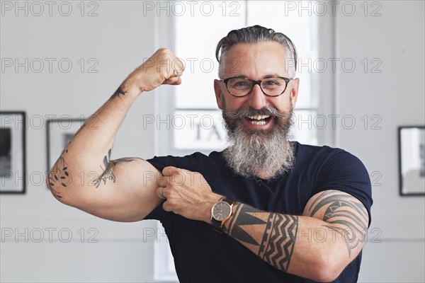 Close up of smiling muscular Caucasian hipster man flexing biceps