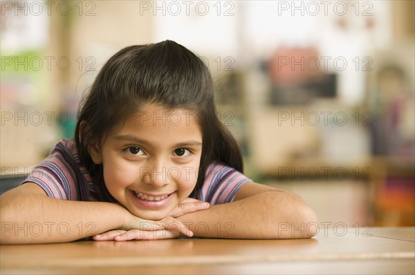 Hispanic girl laying her head on arms