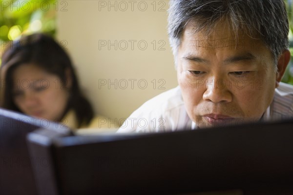 Mature Asian man reading book