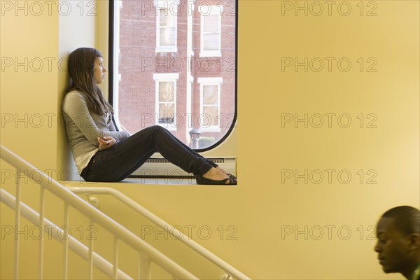 Teenager sitting in window sill