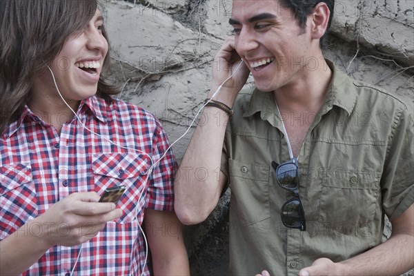 Smiling teenage boys sharing headphones and holding mp3 player