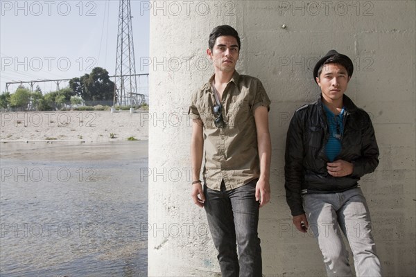 Serious teenage boys leaning against wall