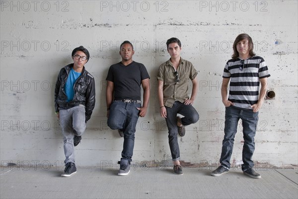 Serious teenage boys leaning against wall