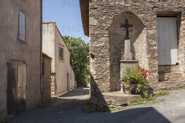 Crucifix shrine in wall alcove on village sidewalk