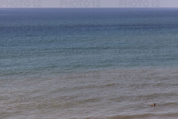 Aerial view of surfer floating on ocean waves