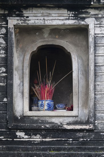 Incense in wall alcove shrine of Buddhist temple