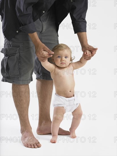 Mixed race father helping baby girl learn to walk