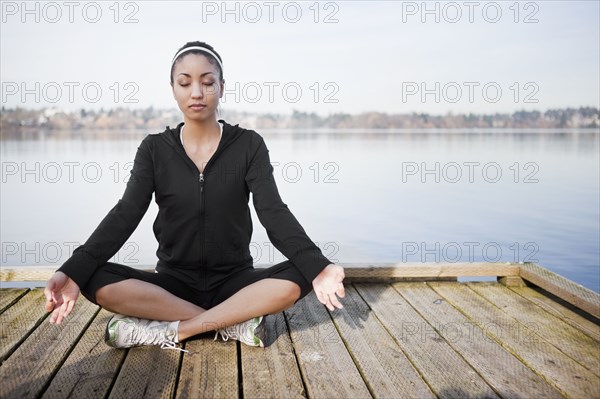 Mixed race woman practicing yoga on pier