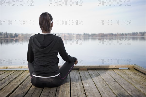 Mixed race woman practicing yoga on pier