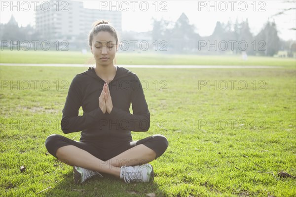 Mixed race woman practicing yoga in park