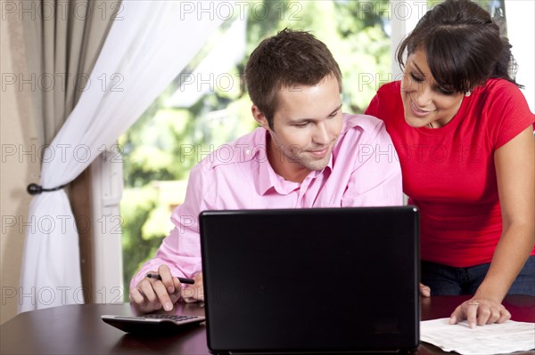 Couple paying bills and using laptop and calculator