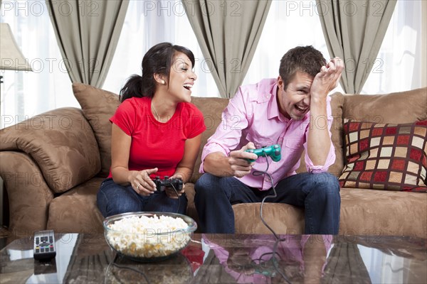 Couple sitting on sofa and playing video game