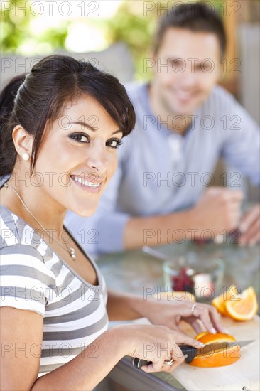 Hispanic woman slicing oranges on patio