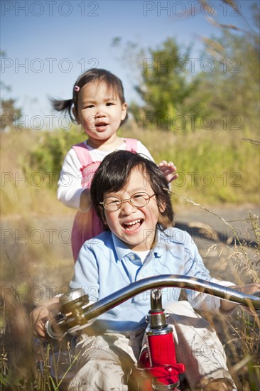 Chinese brother and sister riding tricycle