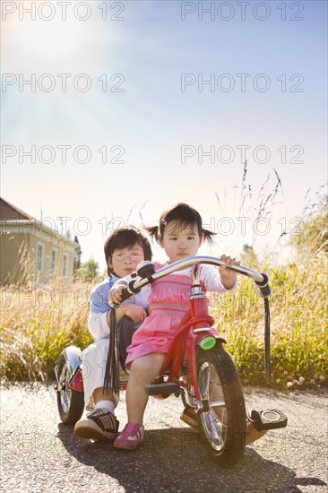 Chinese brother and sister riding tricycle