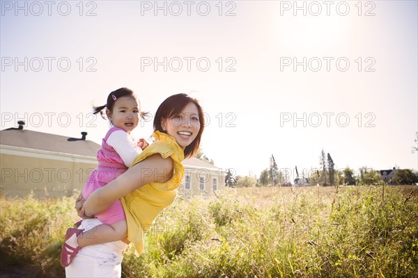 Chinese mother giving daughter piggyback ride