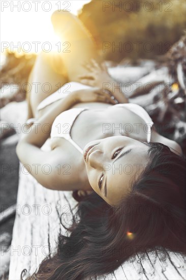 Chinese woman in bikini laying on log