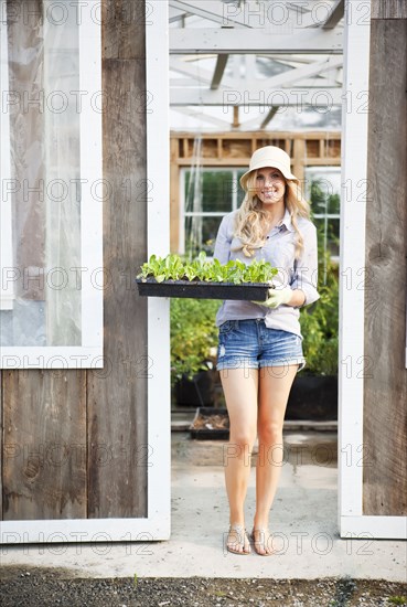 Caucasian woman holding tray of plants