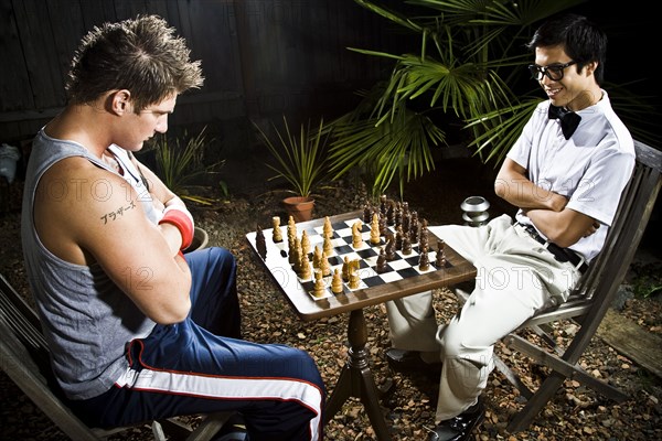 Geek and body builder playing chess