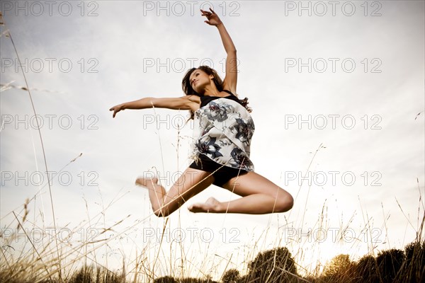 Mixed race woman jumping in mid-air outdoors