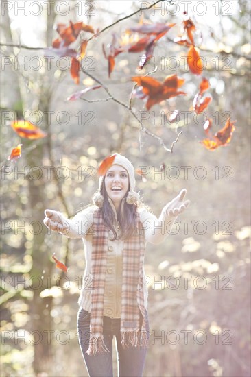 Mixed race woman in cap playing in autumn leaves